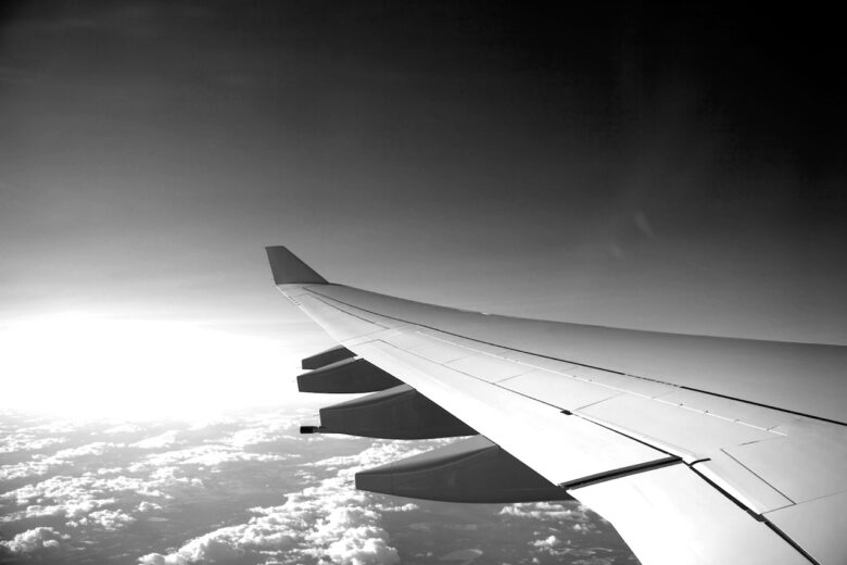 A grayscale airplane wing above the clouds.